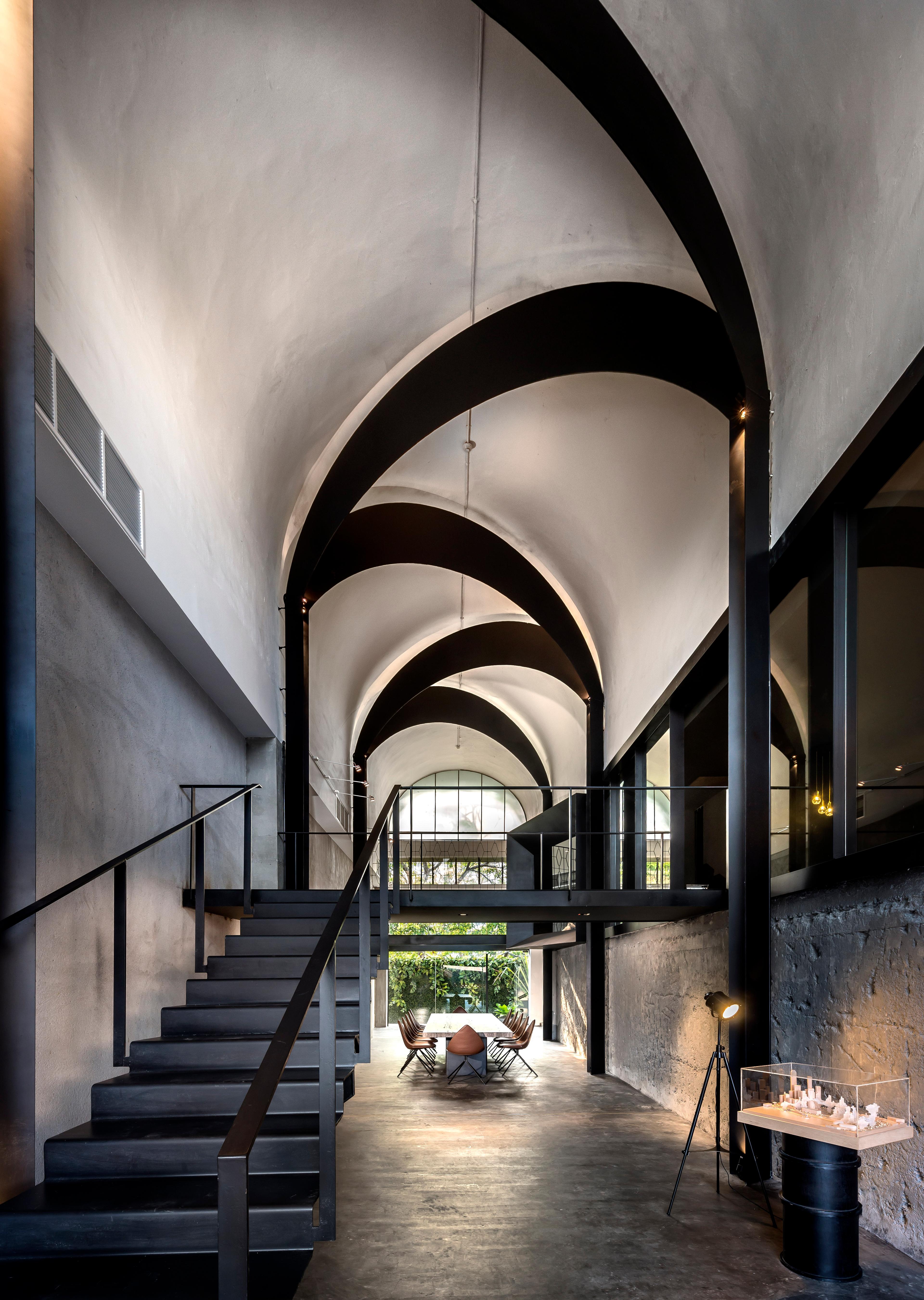 An existing barrel-vaulted ceiling is brought into focus through the insertion of black steel arcs, heightening the spatial depth and marking a quiet moment of arrival.